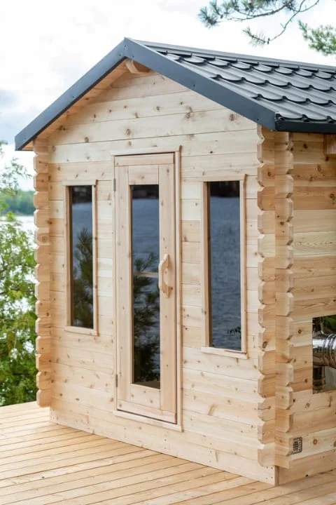 Front entrance of Dundalk CT Georgian traditional sauna featuring full-length glass door and windows with a metal shingle roof