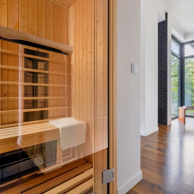 Glass-door infrared sauna installed in modern home with hardwood flooring