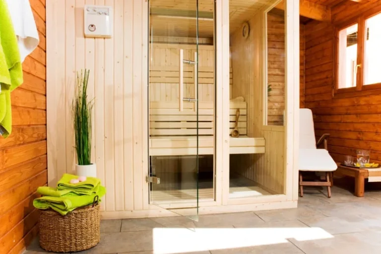 Residential sauna with glass door entrance, decorative green accents, and spa-like atmosphere