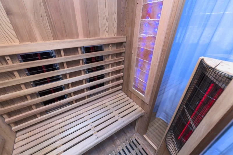 Interior of an infrared sauna with close-up of infrared heating elements and wooden bench