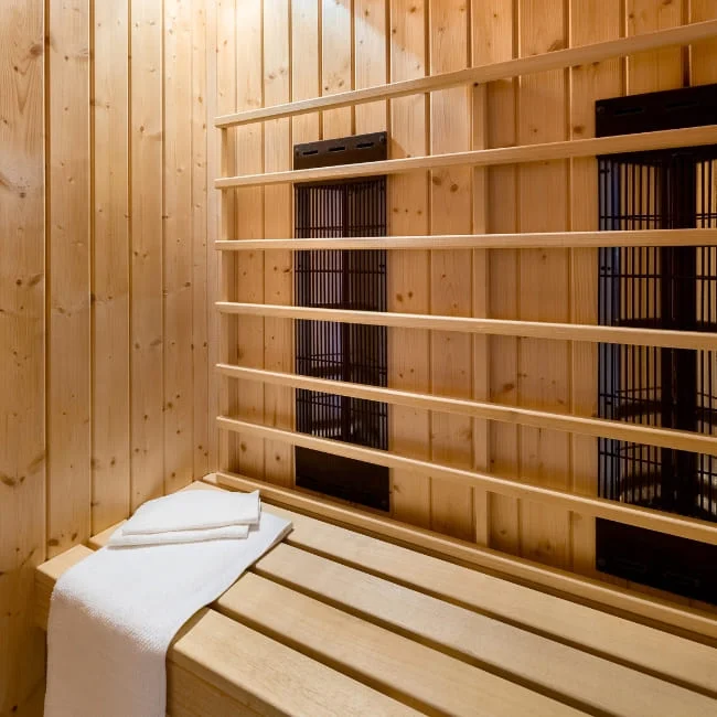 Interior detail of infrared sauna showing wooden bench and heating panels with white towel