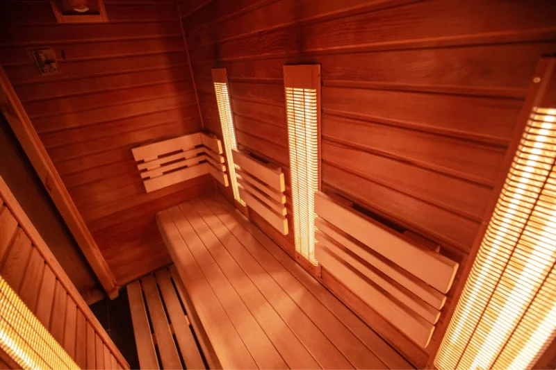 Inside view of wooden infrared sauna with bench seating and infrared heating panels