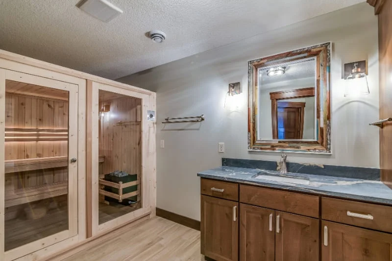 Dual-room sauna installation in master bathroom with marble countertops and custom wood cabinetry