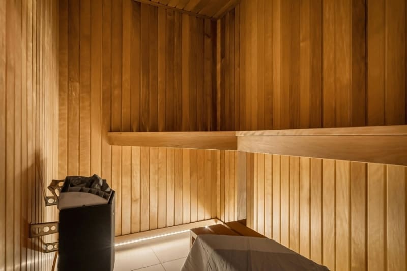 Interior of a traditional wooden sauna with tiered benches and an electric sauna heater