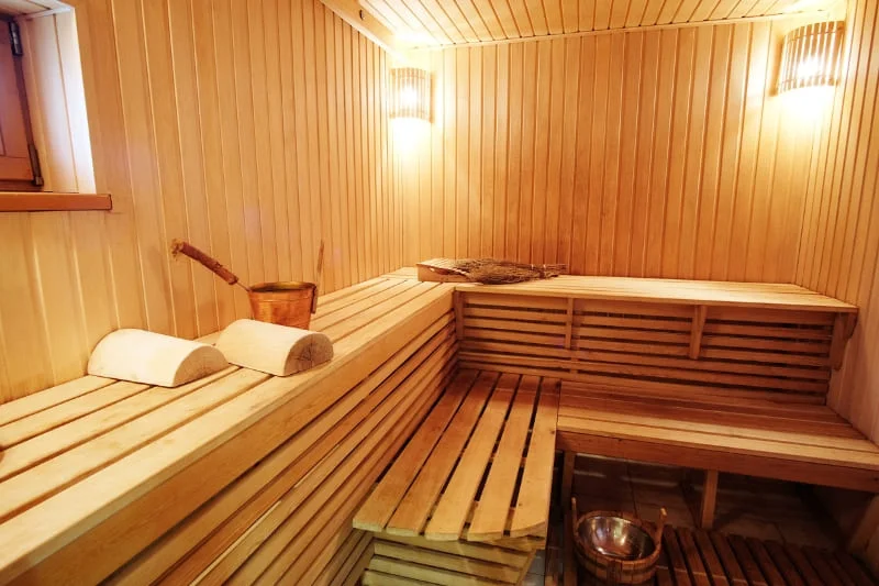 Modern sauna interior featuring wooden panels, comfortable benches, and traditional sauna bucket with ladle.