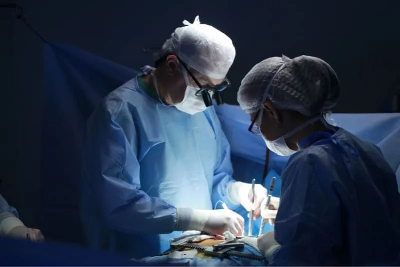 Medical professionals in surgical attire performing operation in hospital operating room, demonstrating procedures that require proper post-operative recovery care.