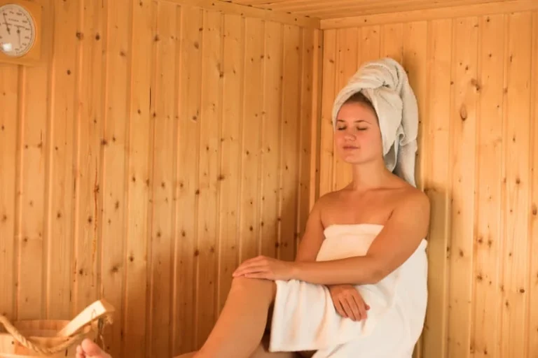 Woman relaxing in traditional wooden sauna during therapeutic heat session