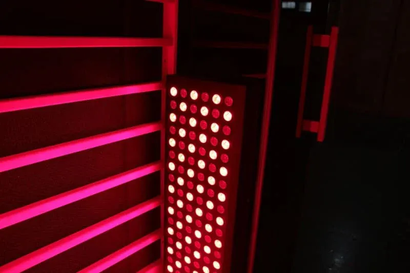 Combination red and white LED therapy panel mounted on sauna wall, showing a grid pattern of alternating red and white light bulbs.