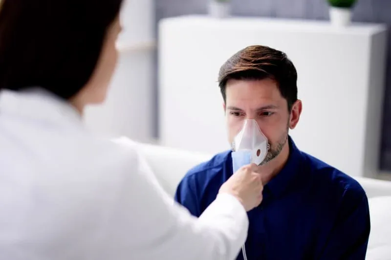 Healthcare provider administering nebulizer treatment to patient with respiratory condition such as COPD or emphysema.