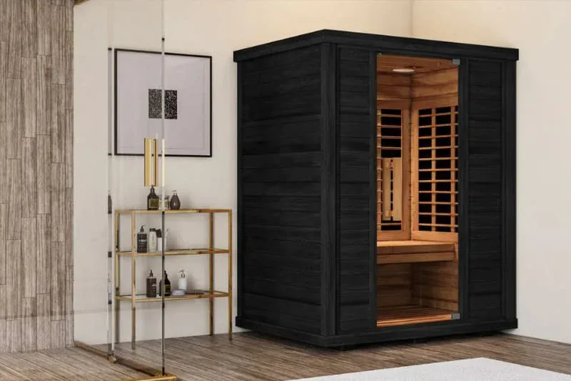 Sun Home Equinox infrared sauna with black exterior and cedar interior featuring glass door, installed in modern home spa setting with wooden floors and minimalist decor