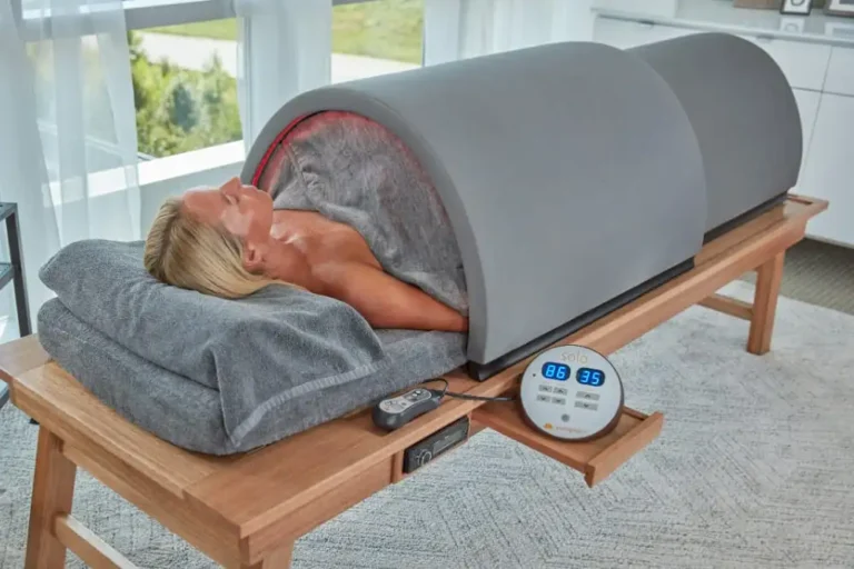 Complete Sunlighten Solo portable infrared sauna setup on wooden stand with user enjoying treatment in bright room.