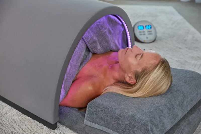 Close-up of Sunlighten Solo sauna with purple chromotherapy lighting illuminating the interior as user relaxes.