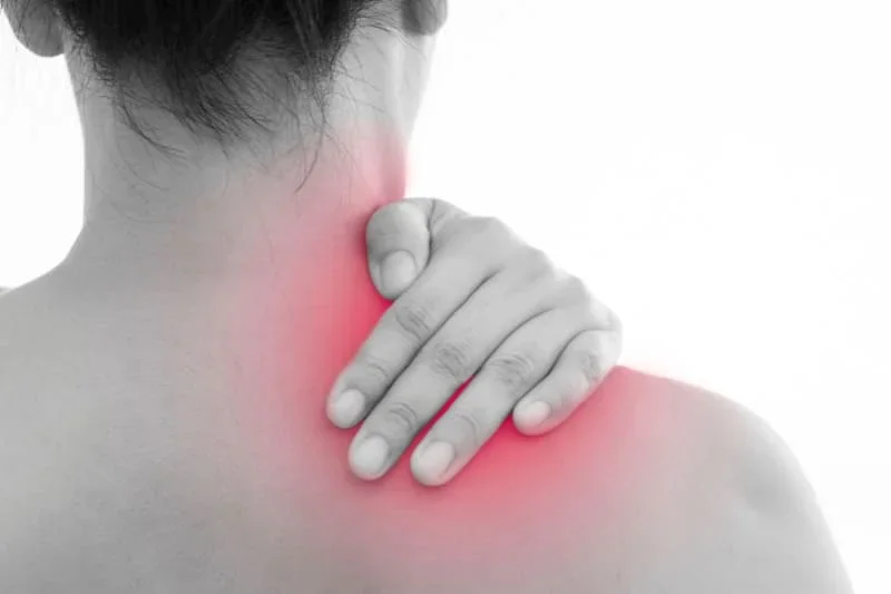 Woman touching painful neck and shoulder area highlighted in red, demonstrating fibromyalgia tender points and muscle pain that can be relieved with sauna therapy