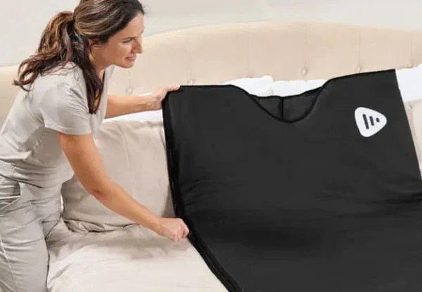 LifePro RejuvaWrap sauna blanket being set up on bed showing easy home use and portability