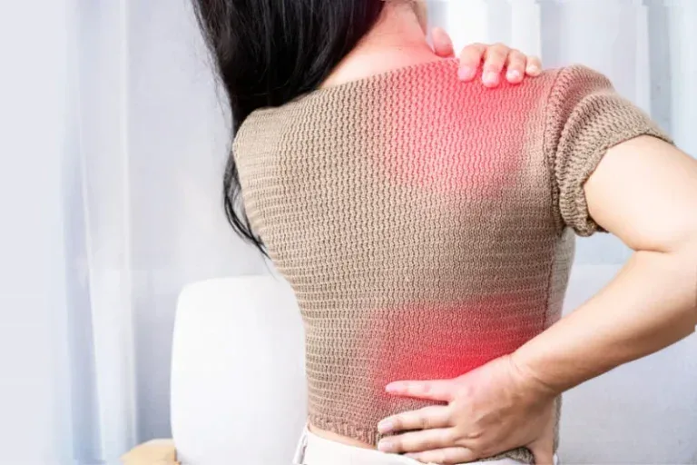 Woman experiencing fibromyalgia pain in neck, shoulder and lower back areas highlighted in red, showing widespread muscle pain that sauna therapy can help relieve