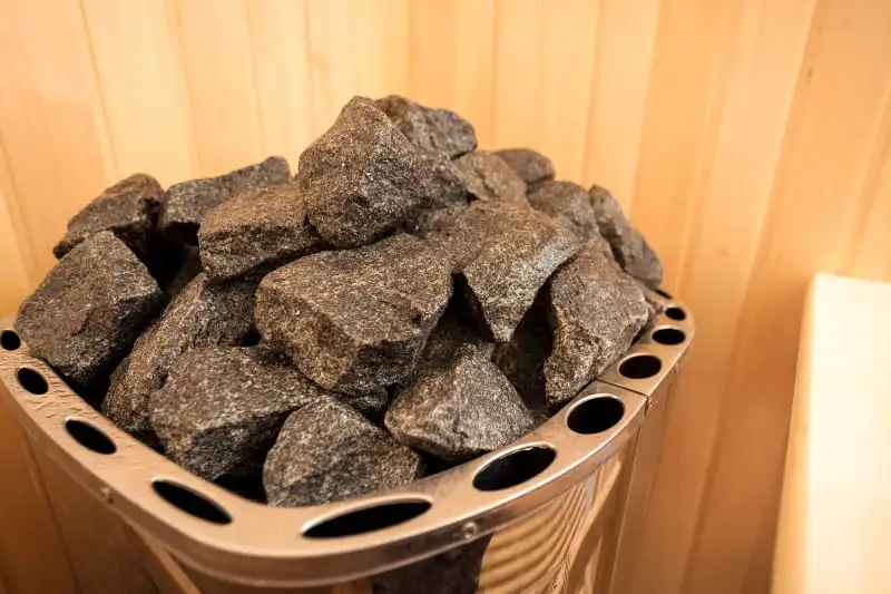 Properly loaded sauna stones in electric heater showing correct stone arrangement and airflow design for maximum heat retention and steam production