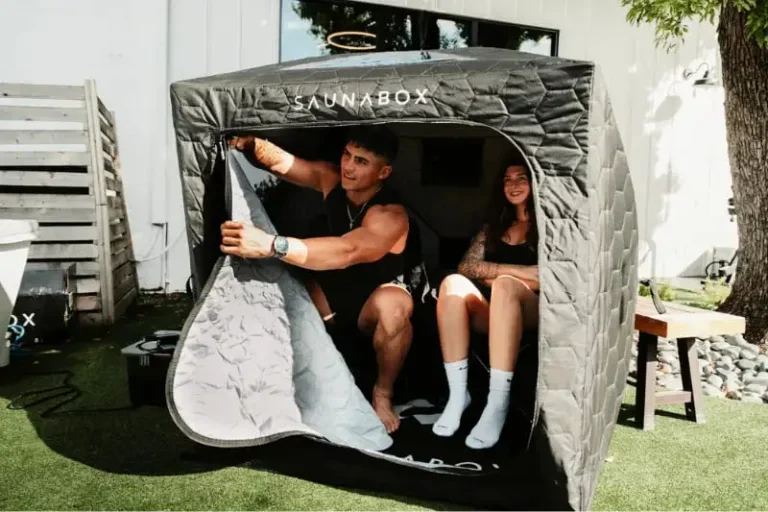 Couple enjoying steam therapy session inside SaunaBox GO two-person portable sauna tent in backyard