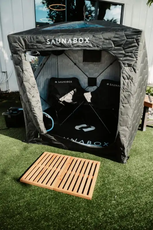 SaunaBox GO portable steam sauna set up outdoors with wooden floor mat and heating unit for couples therapy