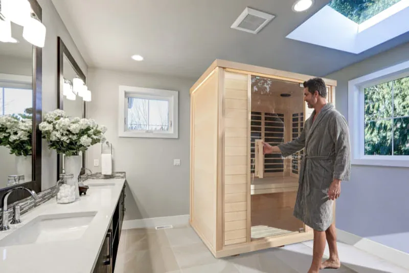Man in robe using Sunlighten Amplify infrared sauna installed in a luxury bathroom