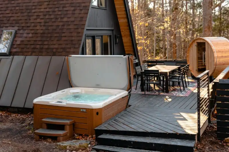 Residential hot tub installation on wooden deck with cover, a barrel sauna and outdoor furniture"