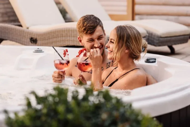 Happy couple relaxing in well-maintained hot tub with drinks.