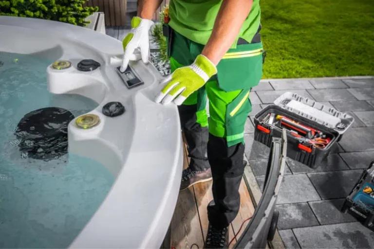 Professional hot tub technician in green uniform performing maintenance with specialized tools and equipment