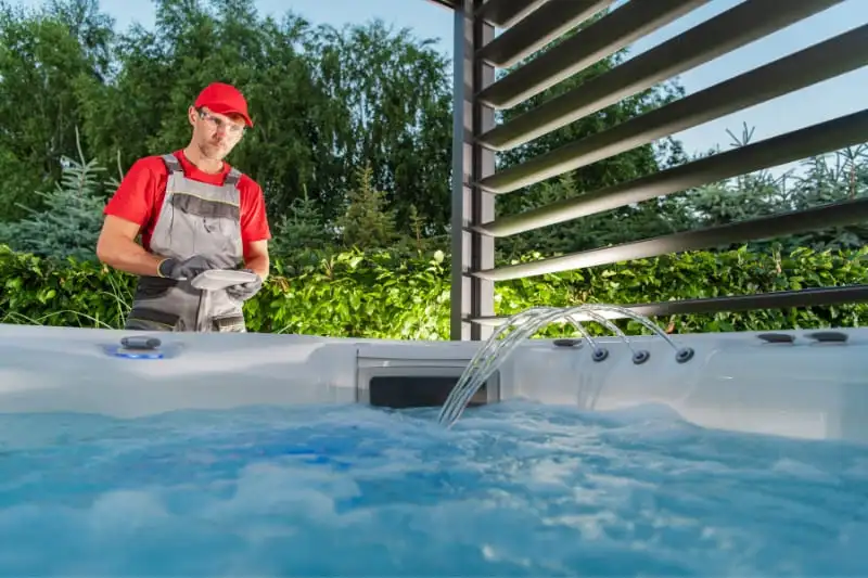 Technician in red uniform testing hot tub water quality and chemical balance during routine maintenance