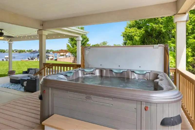 Well-maintained luxury hot tub on covered deck with lake view showing proper spa care results