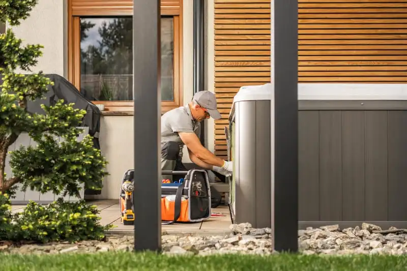 Professional hot tub removal service technician dismantling spa equipment in residential backyard setting
