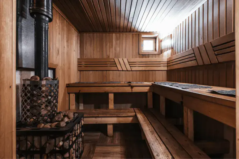 Traditional Finnish sauna interior with wooden benches, heater, and sauna stones