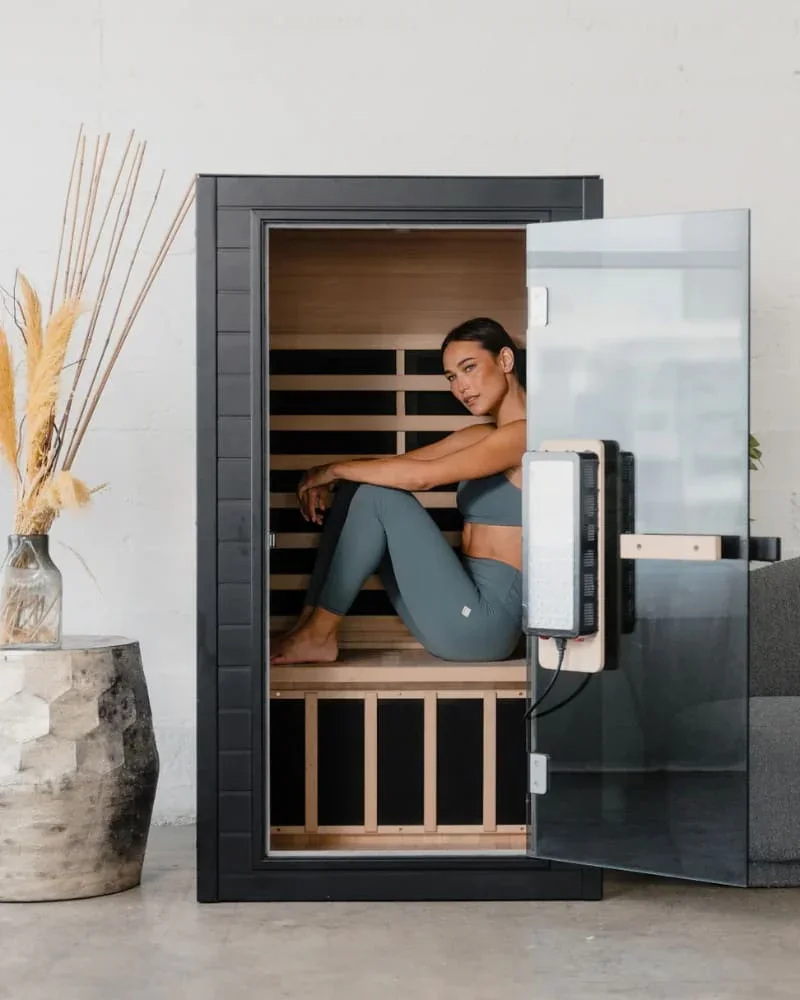 Woman sitting comfortably inside the SaunaBox Solara infrared sauna with door open