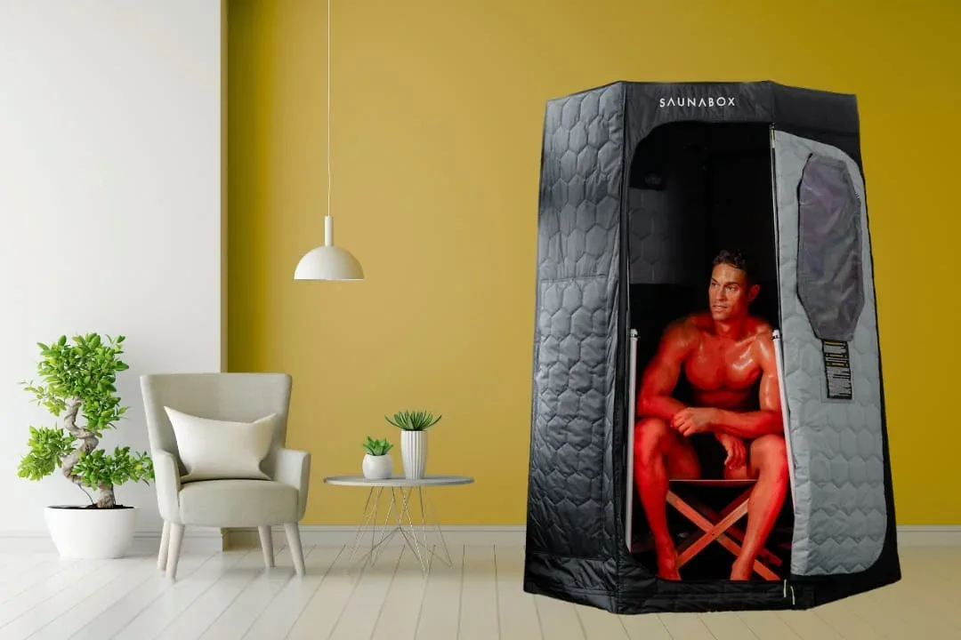 SaunaBox Pulse Pro portable infrared sauna in stylish modern living room with man using Infrared and red light therapy for home wellness